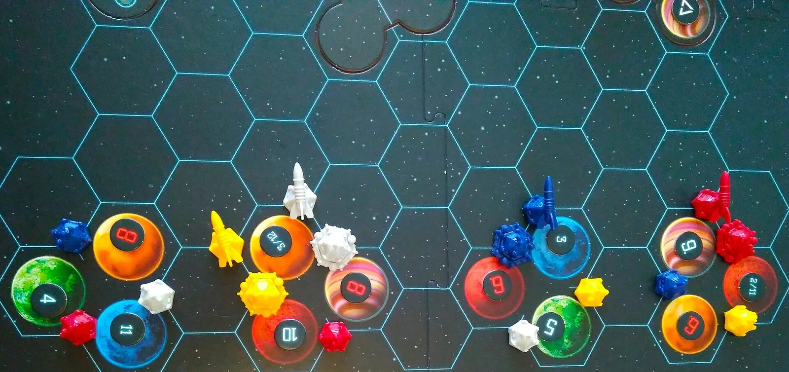 Nahaufnahme des Startaufbaus mit Planeten, Raumschiffen und Kolonieplättchen auf dem Sternenfeld-Spielplan.