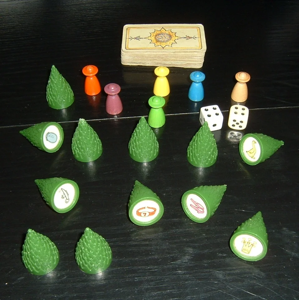 Spielmaterial von Sagaland: grüne Tannenbaumkegel mit Bildplättchen, bunte Spielfiguren, zwei Würfel und ein Kartenstapel auf dunklem Tisch.