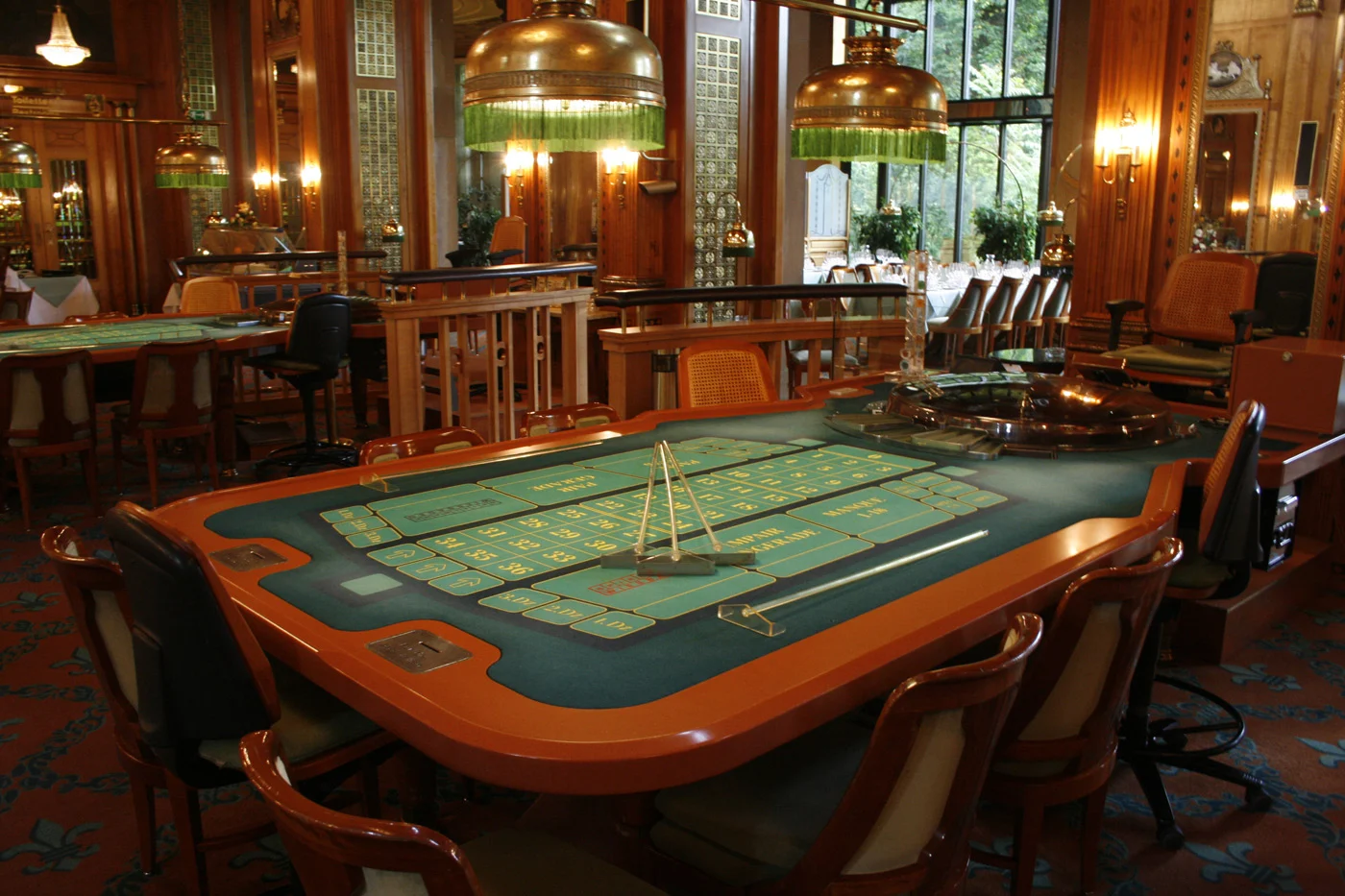 Roulettetisch mit grünem Tableau und Kessel in einem holzgetäfelten Spielsaal.