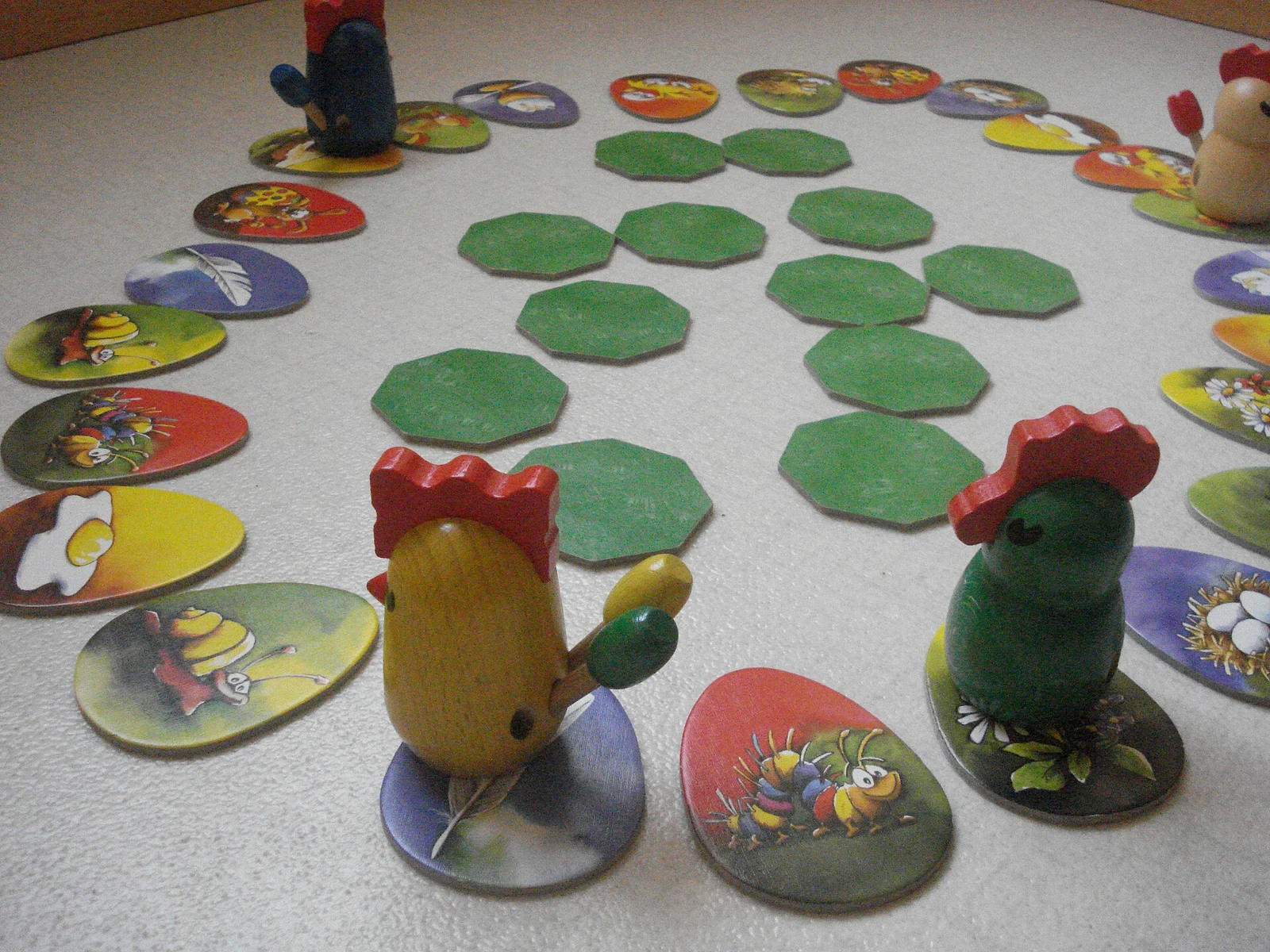 Aufgebaute Spielrunde mit Eierkarten, grünen Achteckplättchen und hölzernen Hühnerfiguren.