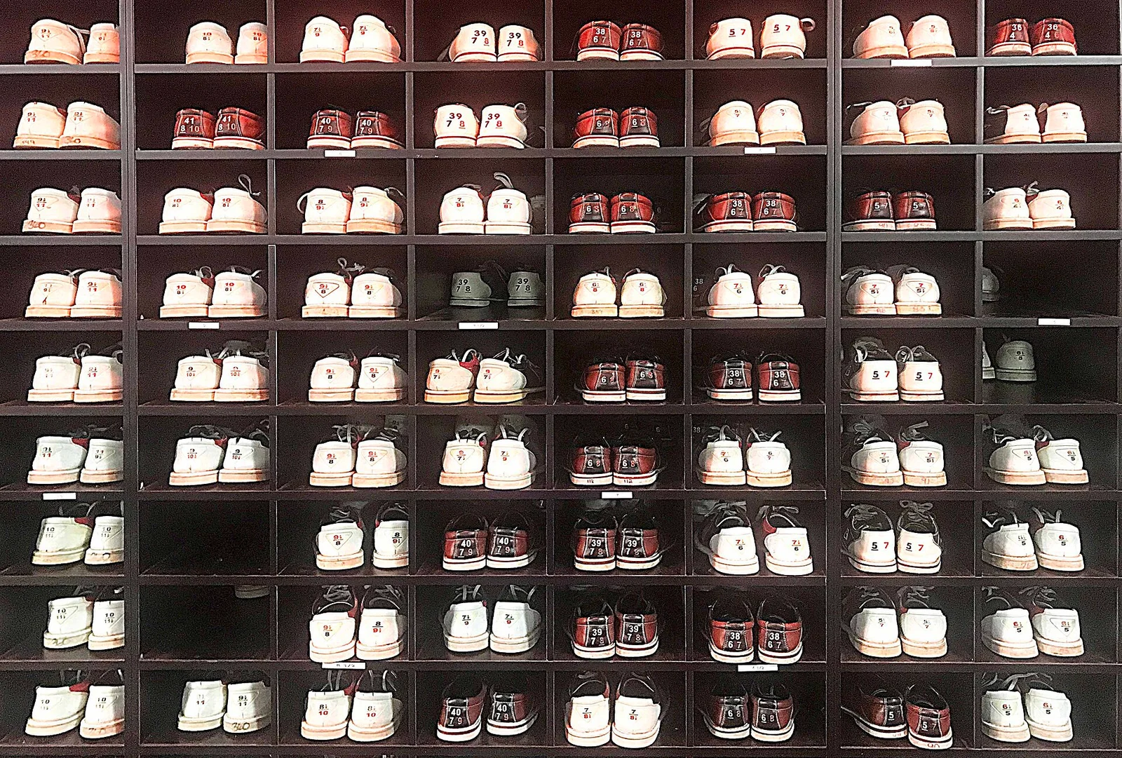 Regal mit vielen Paaren nummerierter Leih-Bowlingschuhe.