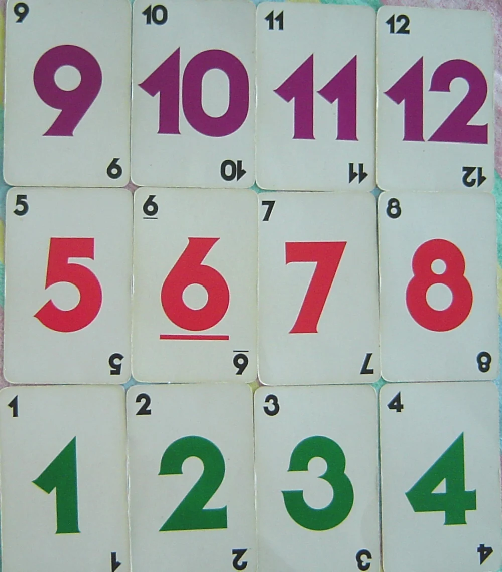 Zwölf ältere nummerierte Spielkarten von 1 bis 12 in Grün, Rot und Violett.