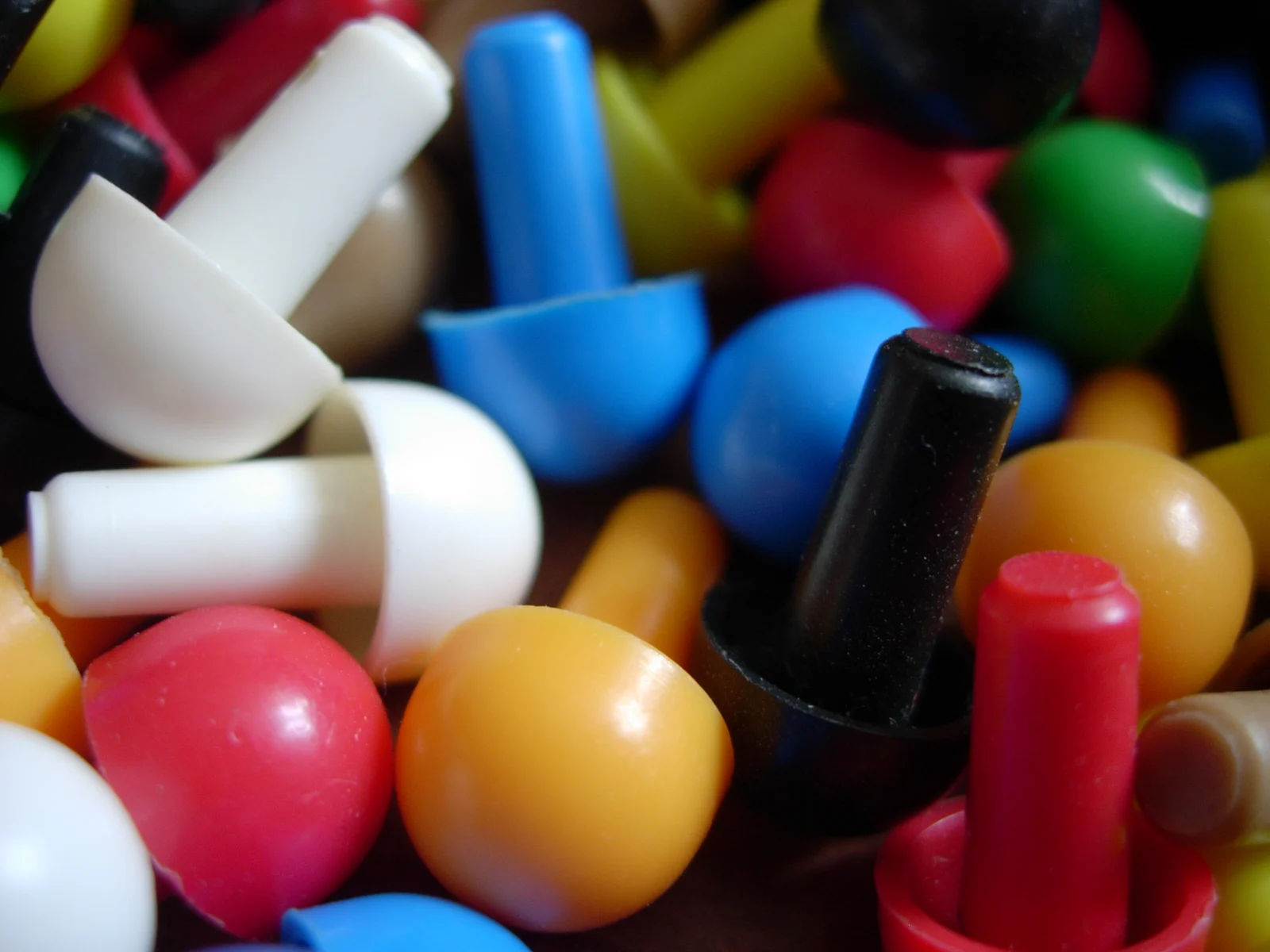 Nahaufnahme bunter Kunststoffstecker in verschiedenen Farben, wie sie als Spielsteine verwendet werden.
