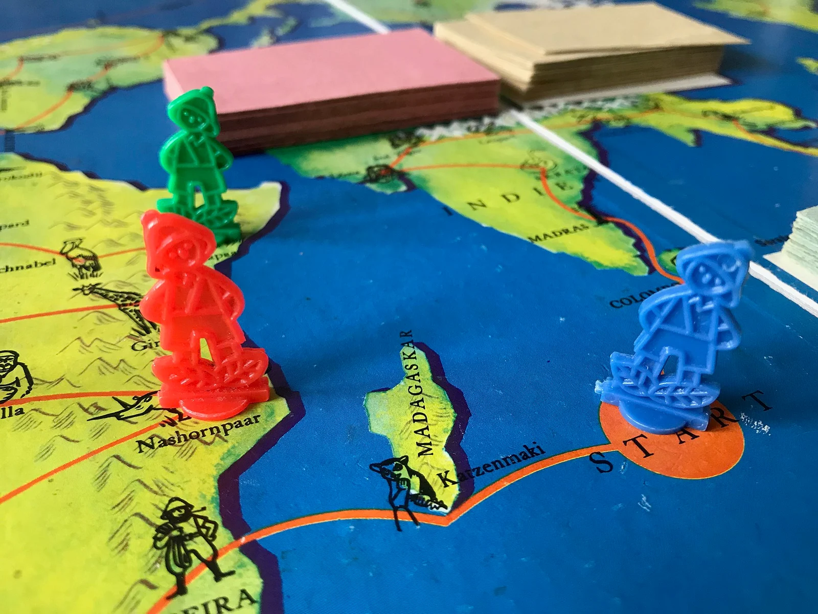 Nahaufnahme des Spielplans mit Weltkarte, farbigen Spielfiguren und Kartenstapeln.
