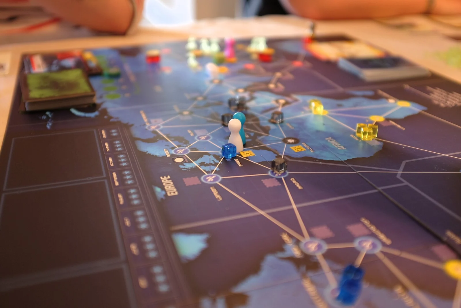 Unscharfe Nahaufnahme eines Weltkarten-Spielplans mit Spielfigur und farbigen Würfeln.