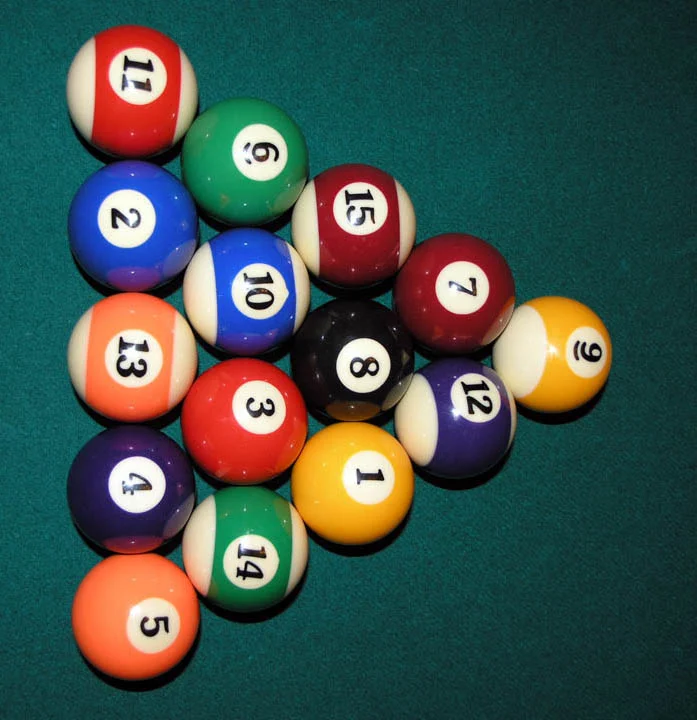 Aufgebaute Dreiecksformation aus 15 nummerierten Billardkugeln mit der schwarzen 8 in der Mitte auf grünem Tuch.