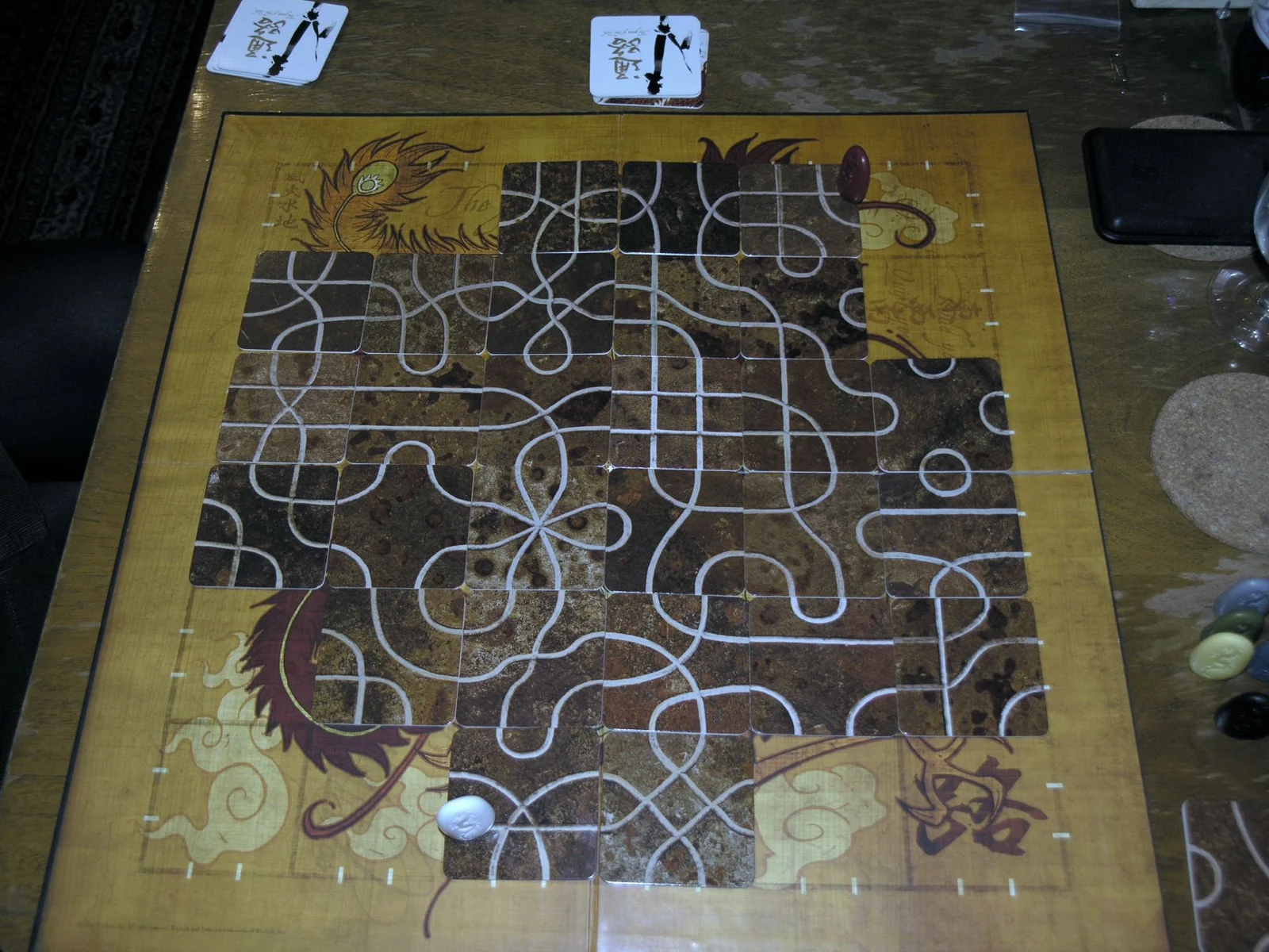 Spielplan mit ausgelegten Wegeplättchen und Spielsteinen von oben fotografiert.