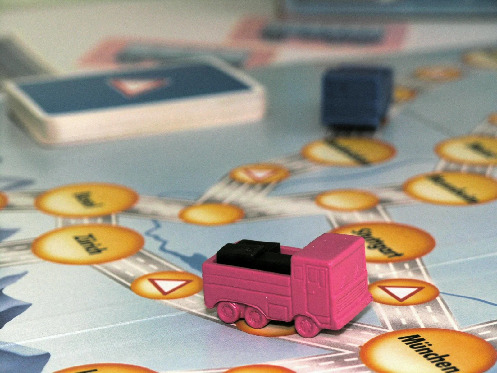 Pinker Lastwagen mit schwarzer Ladung auf dem Spielplan mit Städtefeldern.