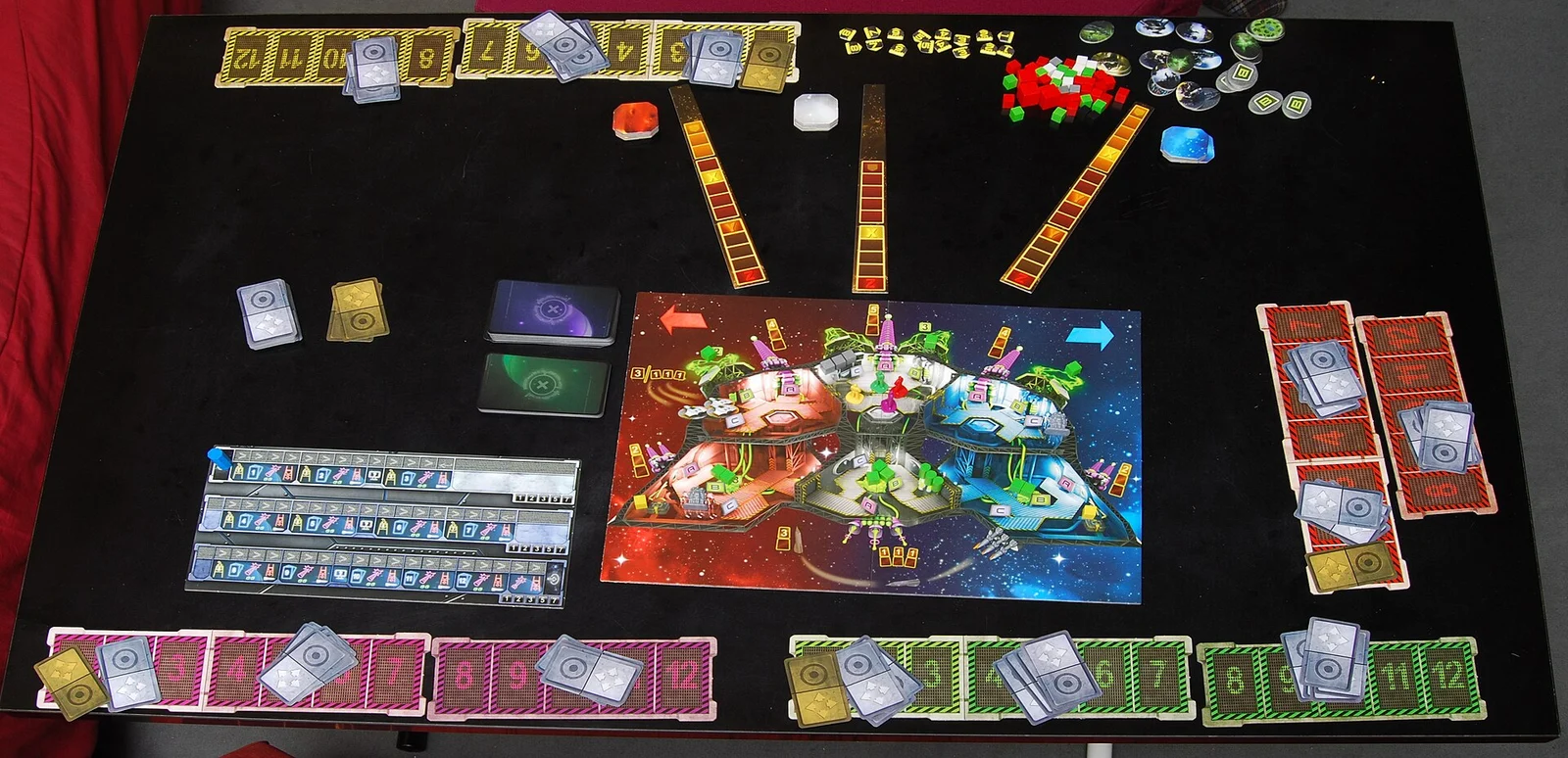 Vollständig aufgebauter Spielplan mit Raumschiffplan, Karten, Leisten und Marken auf einem schwarzen Tisch.